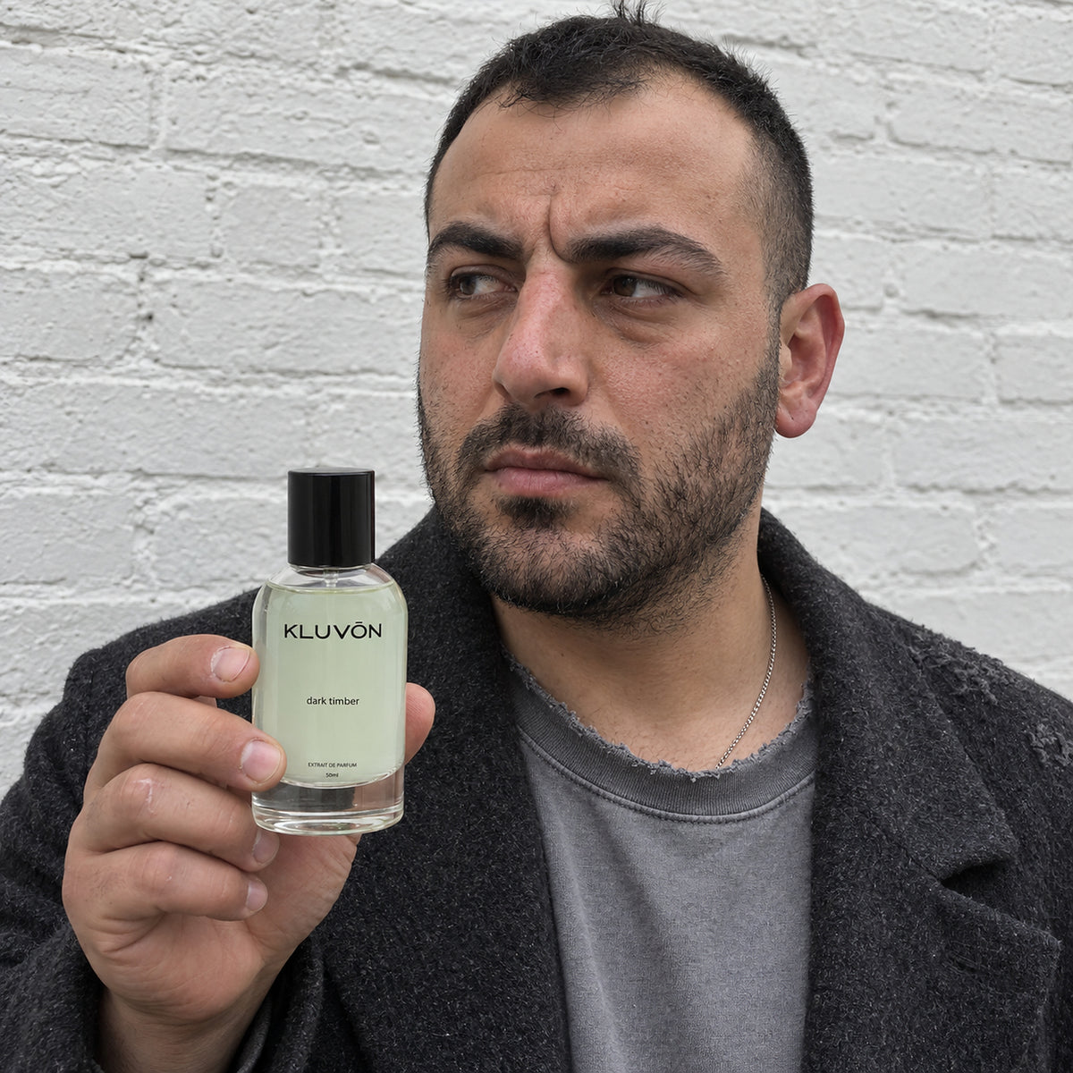 Mand med Kluvon dark timber extrait de parfum foran hvid murstensvaeg